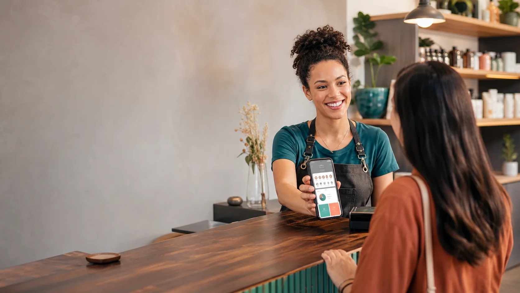 Dona de pequeno negócio apresentando um cartão fidelidade digital para uma cliente.